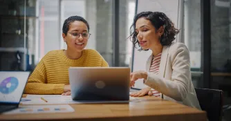 Zwei Business Frauen sitzen vor einem Laptop und setzen ihr Wissen aus dem E-Commerce Studium ein