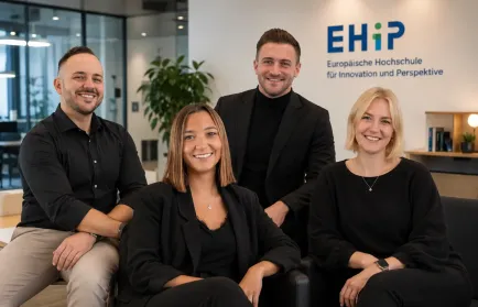 Vier lächelnde Teammitglieder posieren in einem Büro vor einer Wand mit dem Schriftzug EHiP.