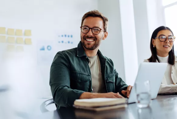 Perspektiven mit dem Studium Business Mann am Laptop mit Brille lächelt
