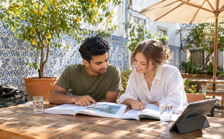 Hochschulkooperationen der EHiP: Zwei Studierende lernen im sonnigen Innenhof in Lissabon