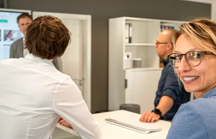 Vier Personen stehen im Gespräch an einem hohen Tisch in einem hellen Büro.