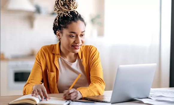 Junge Frau sitzt lernend vor ihrem Laptop