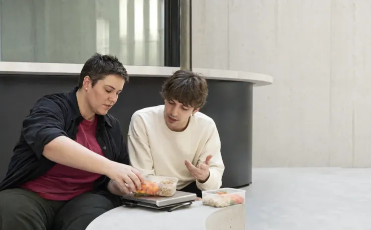 Ernährungsberaterin wiegt gemeinsam mit einem Klienten Lebensmittel für einen Ernährungsplan ab