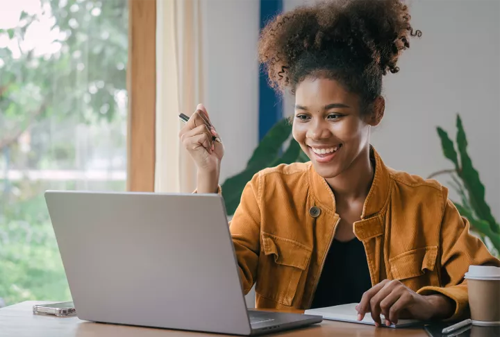 Inhalte Studium Eine Studentin sitzt lachend vor ihrem Laptop