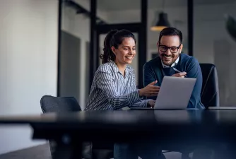 Studiendauer anpassen Eine Frau und ein Mann sitzen im Büro vor einem Laptop