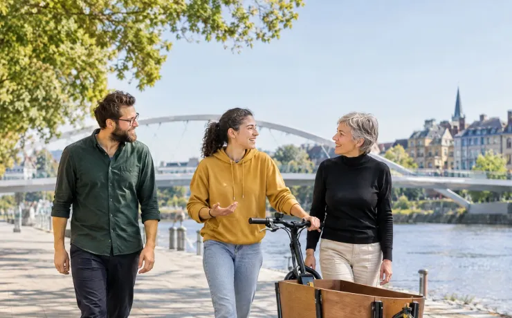 Drei Kolleginnen und Kollegen gehen lachend eine Uferpromenade entlang und besprechen unterwegs eine Idee