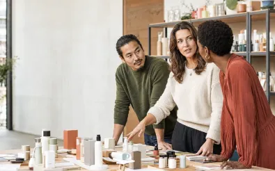 Drei Fachkräfte besprechen an einem Tisch mit Produktmustern und Materialproben eine Sortimentsentscheidung