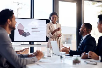 Eine Businessfrau hält im Meetingraum einen Vortrag vor mehreren Männern