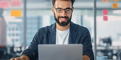 Business Mann sitzt vor Laptop und arbeitet im Büro